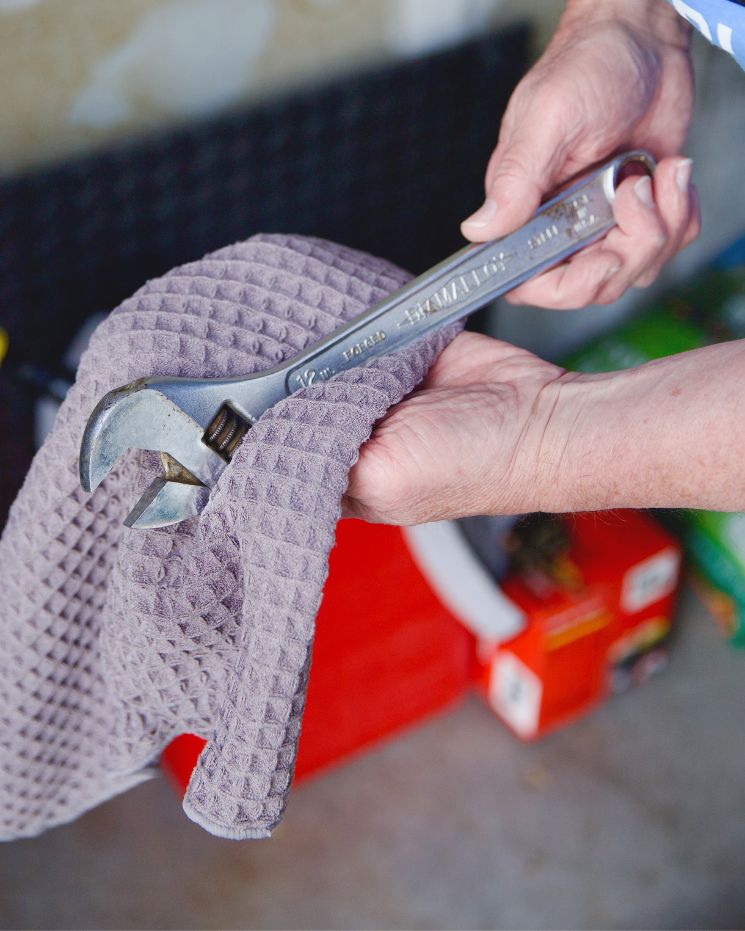 practical father's day gift_5 A person wipes a large adjustable wrench with a textured gray cloth over a red tool box—making it the perfect practical gift for Father’s Day.