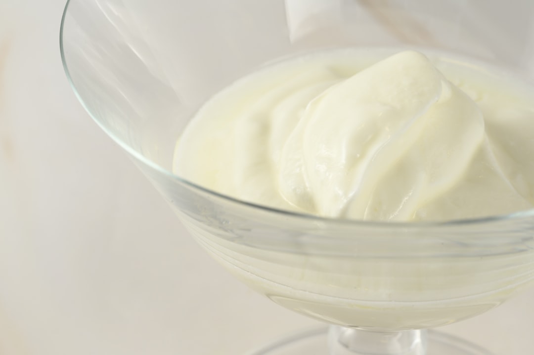 a glass bowl filled with cream on top of a table