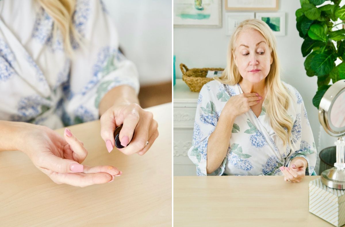 In this beauty edition moment, a woman in a floral robe applies skincare serum to her fingers and then to her neck while seated at a table with a mirror—why didn’t I think of that?.