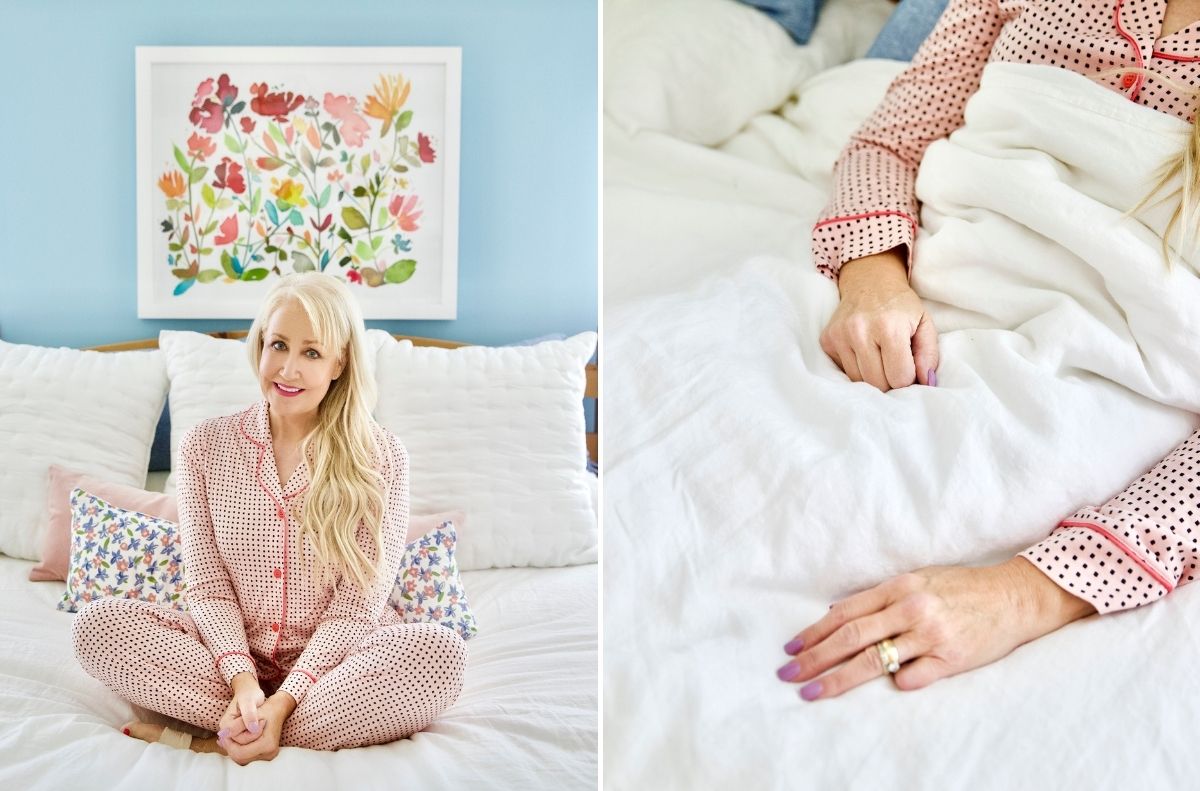 A woman in pink polka dot pajamas sits on a bed with white bedding, exuding a calm mind. A close-up shows her hand with a ring resting gently on the blanket. Behind her, a floral painting hangs on the soft blue wall.