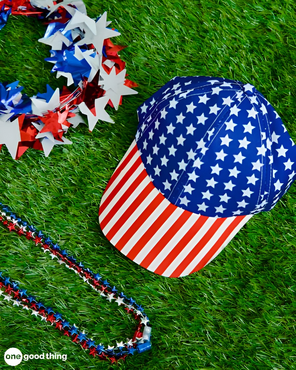 summer-dollar-store11-600x750 A patriotic cap with stars and stripes, red, white, and blue garland, and a beaded necklace from the dollar store lie on green grass.
