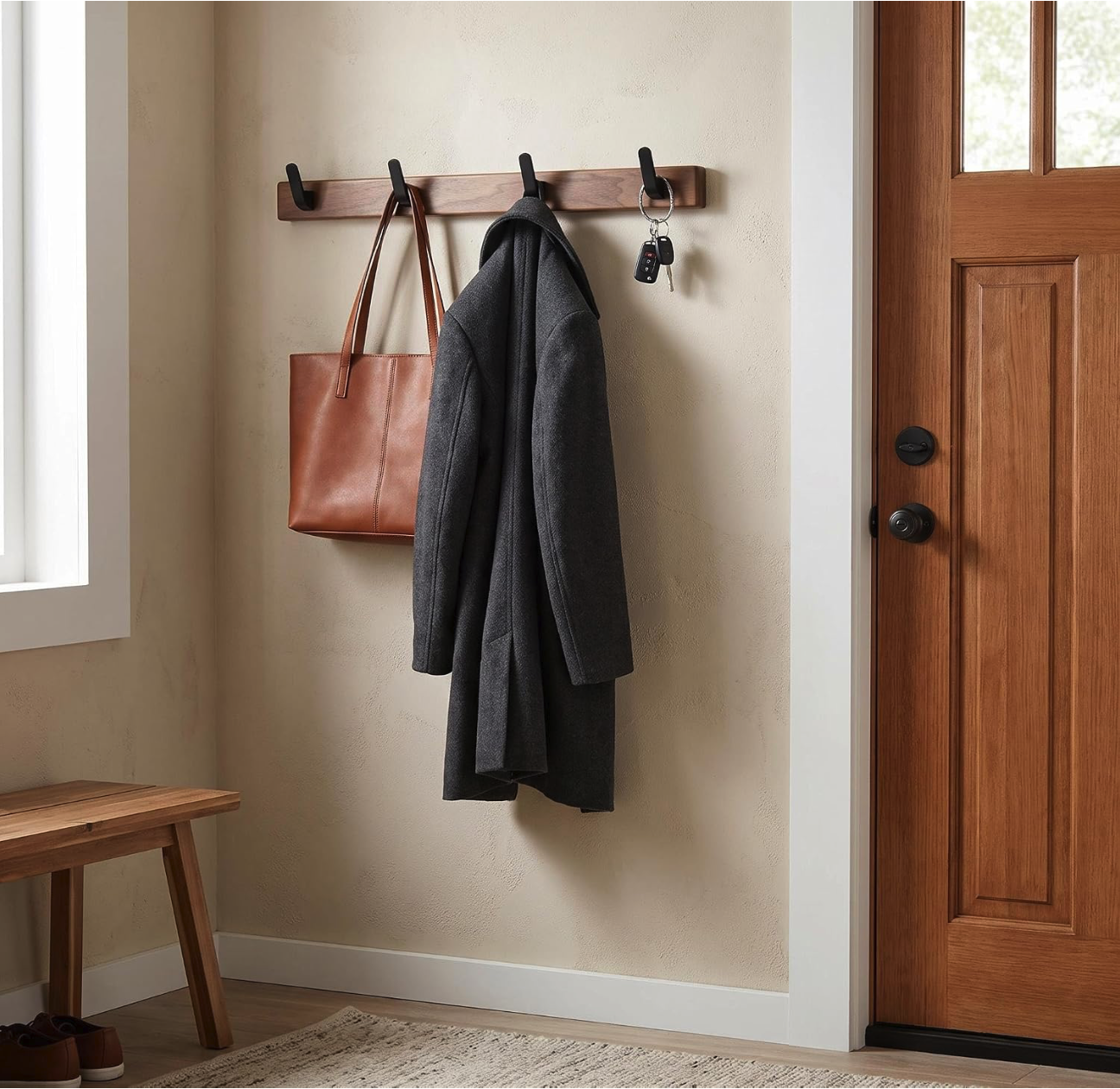 Wooden wall-mounted coat rack with black hooks holding misplaced items including a leather tote bag, a wool coat, and a set of keys.