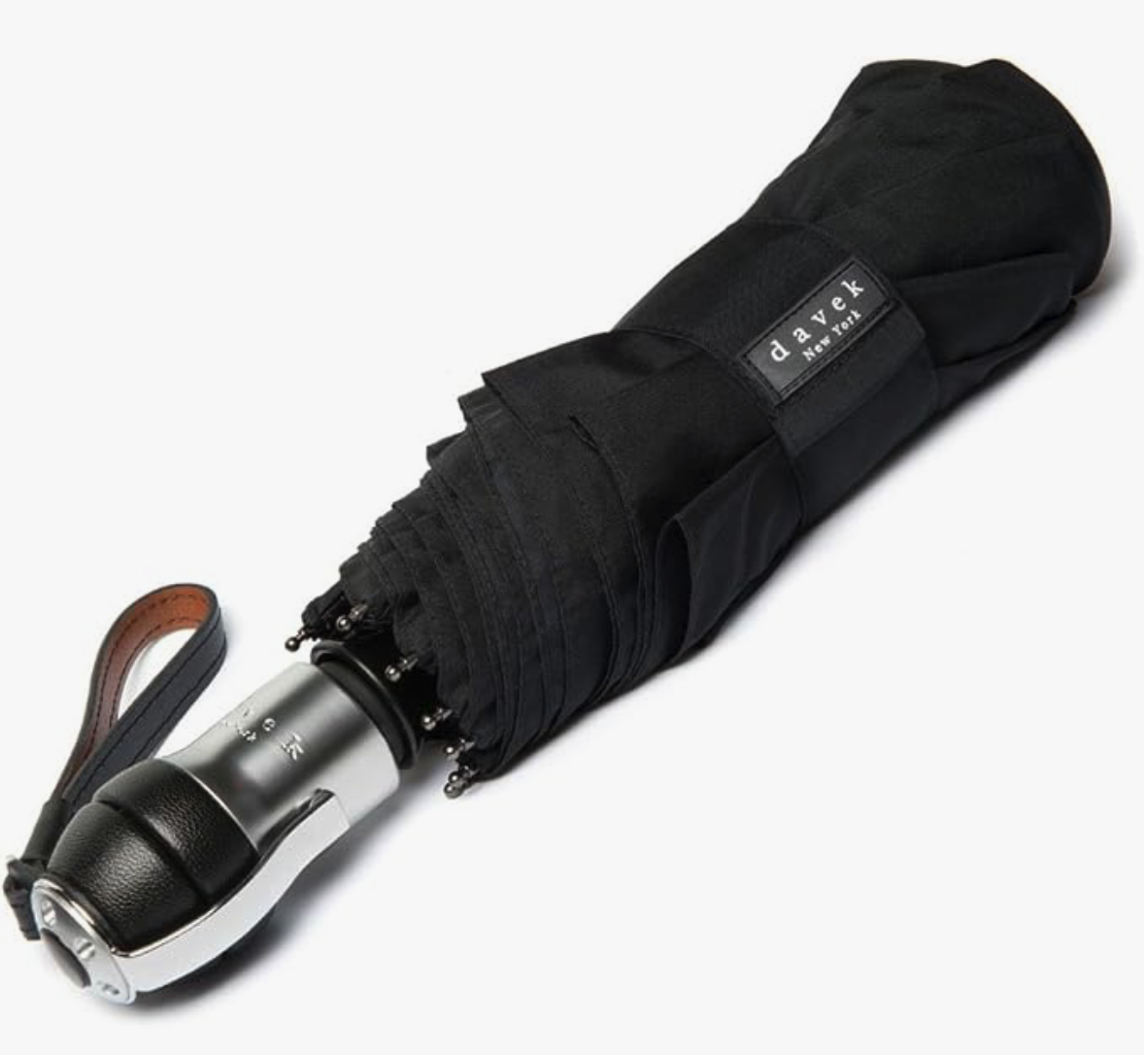 A closed black Davek New York travel umbrella with a silver and leather handle, backed by lifetime warranties.