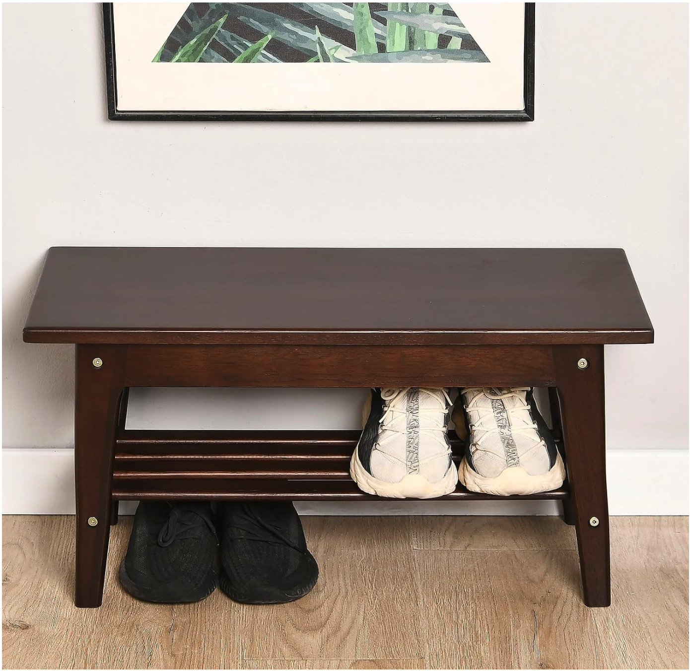A dark wood shoe bench with two pairs of sneakers left as misplaced items on its lower shelf.